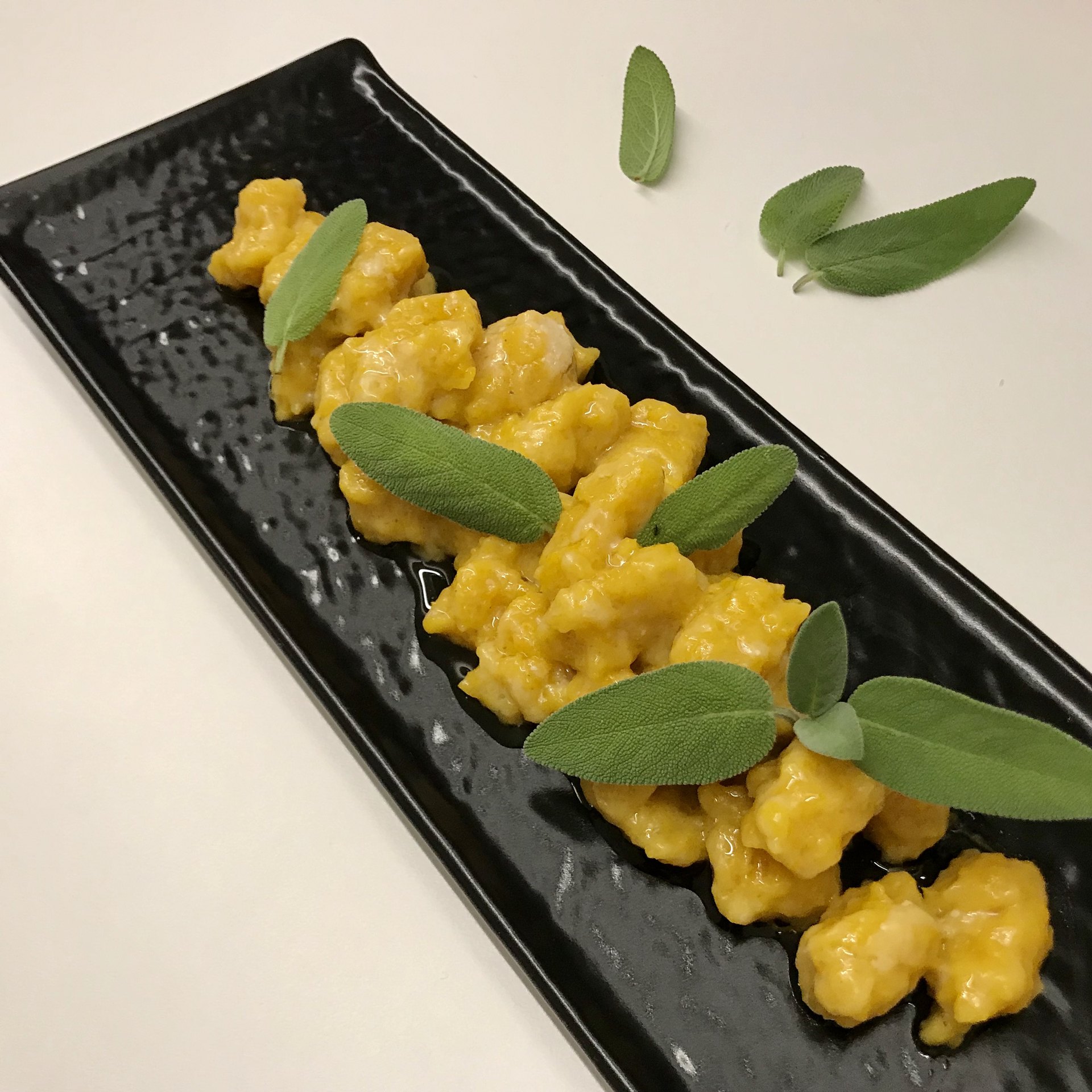 Seasoned pumpkin gnocchi arranged on a dark plate